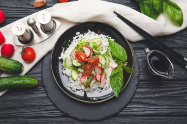 Koyu ahşap arka planda sebzeli lezzetli pirinç salatası.