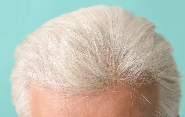 Senior man with grey hair on color background, closeup