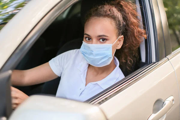 African-American female driver wearing medical mask in car