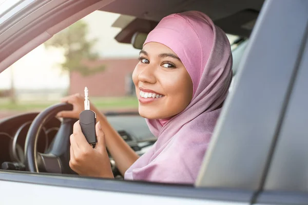 Young Muslim woman with key sitting in new car