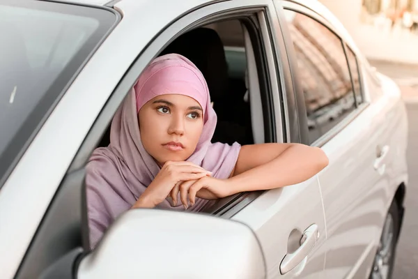 Young Muslim woman sitting in car