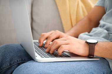 Evde dizüstü bilgisayarda çalışan genç adam, yakın plan.