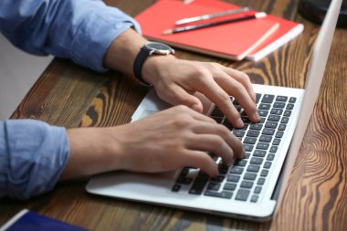 Masada dizüstü bilgisayarda çalışan genç adam.