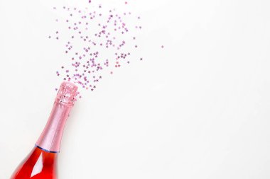 Beyaz arka planda Noel simleri olan bir şişe şampanya.