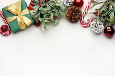 Beyaz arka planda ökseotu dalları ve dekoru olan Noel kompozisyonu