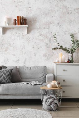 Gri kanepesi ve yanan mumları olan şık bir oturma odası.