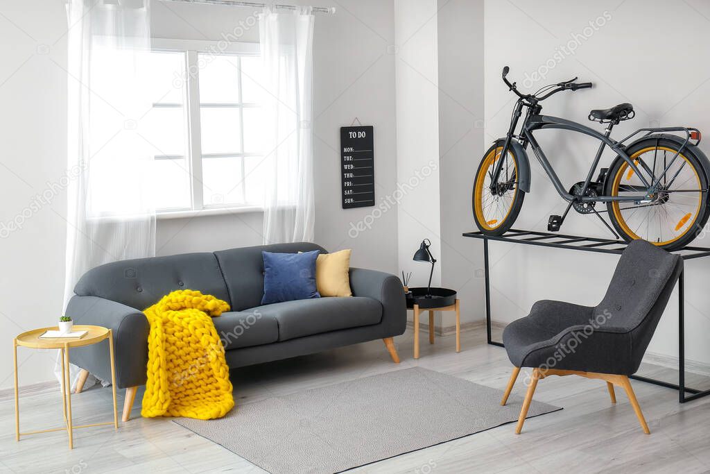 Interior of modern room with bicycle, sofa and knitted plaid