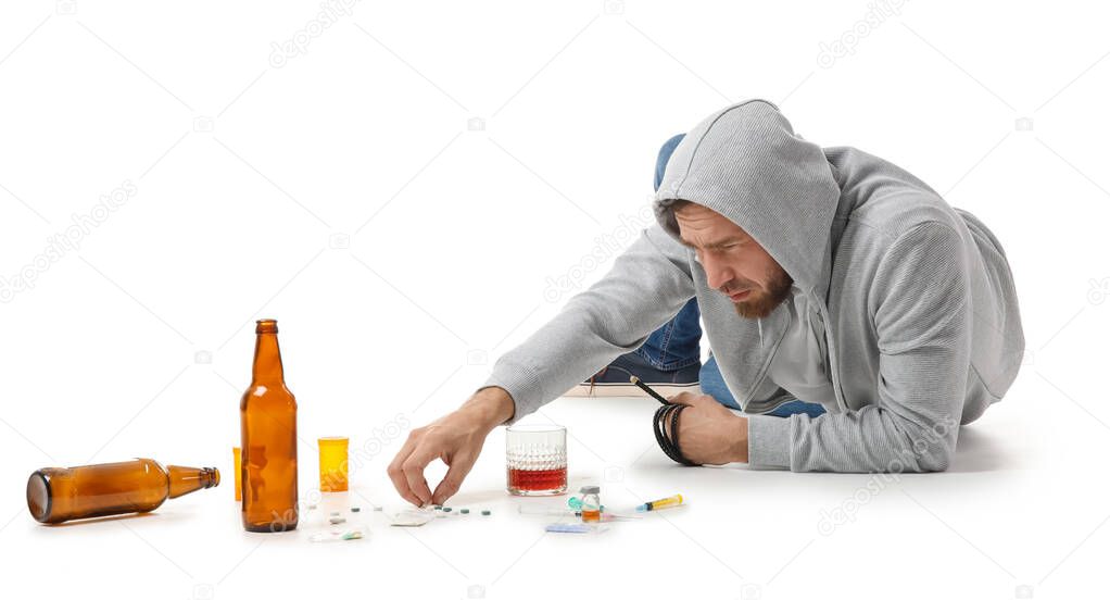 Male junkie with drugs and alcohol on white background. Concept of addiction