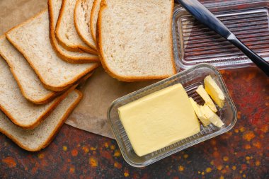 Cam tabakta tereyağı, masada bıçak ve tost.
