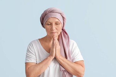 Kemoterapiden sonra hafif arka planda dua eden olgun bir kadın.