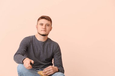 Uzaktan kumandalı ve arka planda patates cipsi olan genç adam.