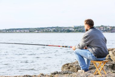 Genç adam nehirde balık tutuyor.
