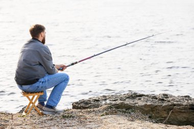 Genç adam nehirde balık tutuyor.