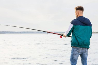 Genç adam nehirde balık tutuyor.