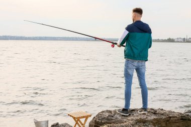Genç adam nehirde balık tutuyor.