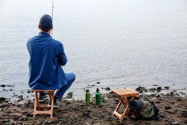 Genç adam nehirde balık tutuyor.
