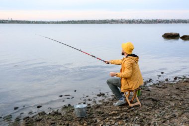 Genç adam nehirde balık tutuyor.