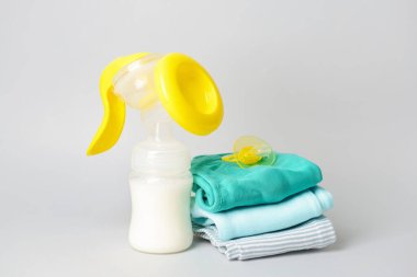 Göğüs pompası ve bebek aksesuarları gri arka planda