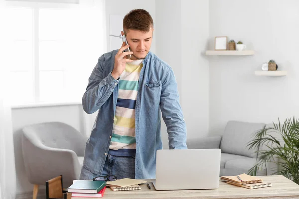 Jovem Falando Por Telefone Enquanto Usa Laptop Casa — Fotografia de Stock