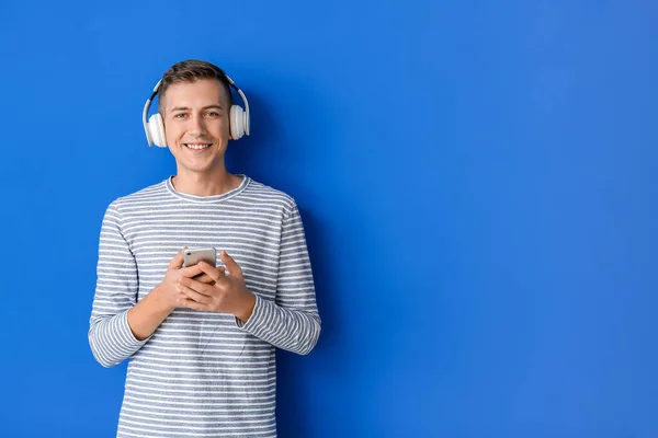 Νεαρός Άνδρας Ακουστικά Και Κινητό Τηλέφωνο Στο Φόντο Χρώμα — Φωτογραφία Αρχείου