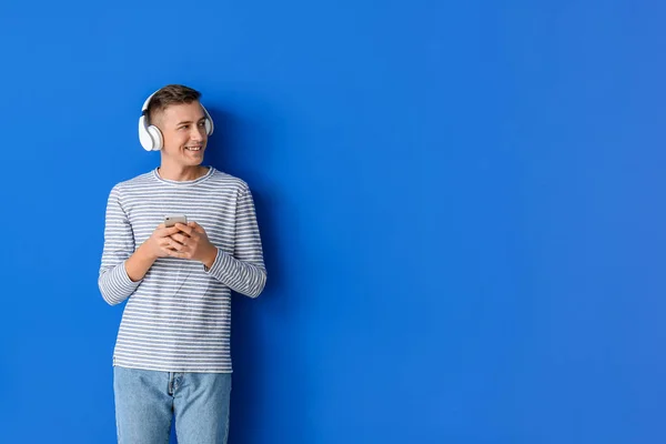 Νεαρός Άνδρας Ακουστικά Και Κινητό Τηλέφωνο Στο Φόντο Χρώμα — Φωτογραφία Αρχείου