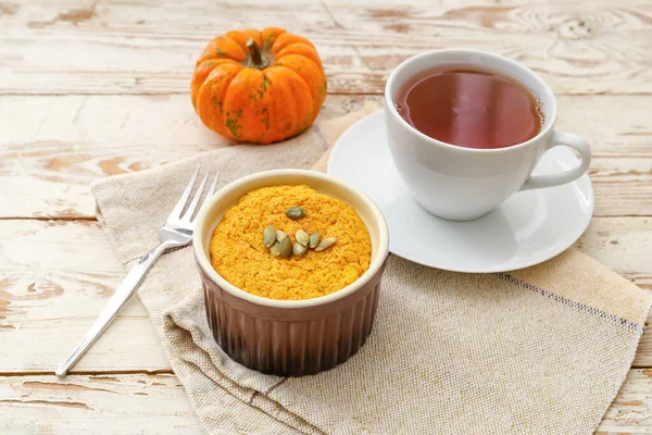Tasty pumpkin pudding with cup of tea on table