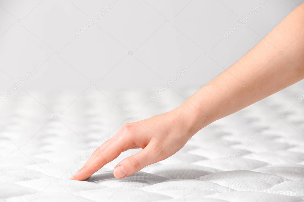 Woman touching soft orthopedic mattress, closeup