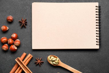 Karanlık arka planda baharatlar olan yemek kitabı.