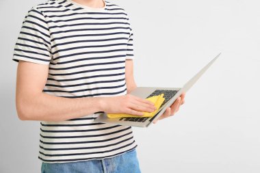 Işık arka planında dizüstü bilgisayarı temizleyen adam