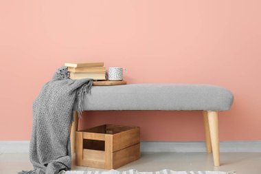 Kitaplı bank, ekose kumaş ve renkli duvarın yanında çay.