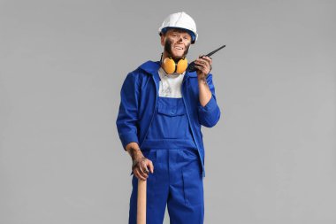 Miner man with pick axe and two-way radio on grey background clipart