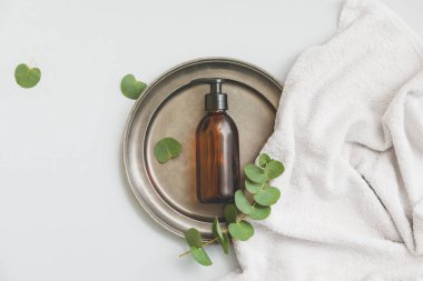 Işık arka planında doğal okaliptüs kozmetiği olan bir şişe.