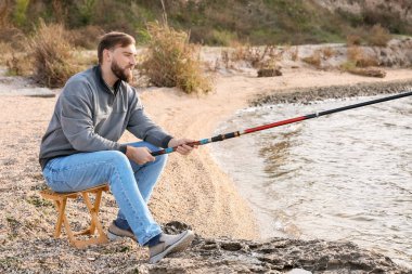 Genç adam nehirde balık tutuyor.
