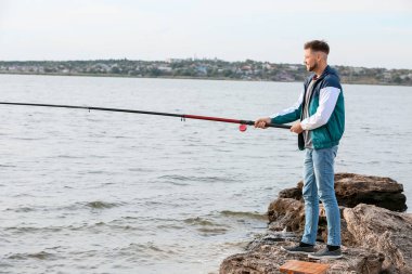 Genç adam nehirde balık tutuyor.