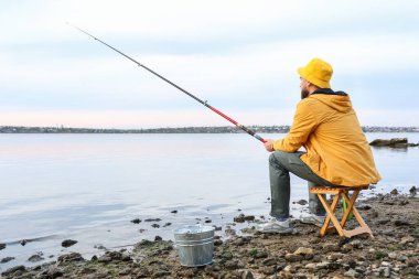 Genç adam nehirde balık tutuyor.