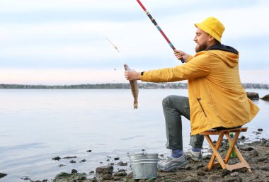 Genç adam nehirde balık tutuyor.