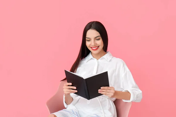 Młoda Kobieta Czyta Książkę Siedząc Fotelu Tle Koloru — Zdjęcie stockowe