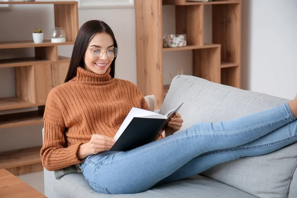 Ung Kvinde Læser Bog Derhjemme - Stock-foto
