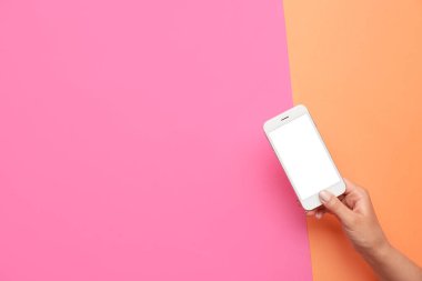 Cep telefonunu renkli arkaplanda tutan kadın