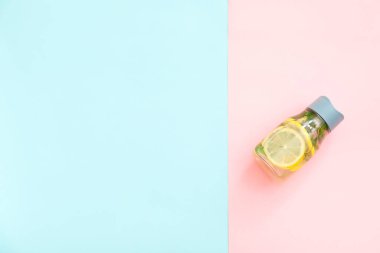 Renkli arkaplanda limonlu ve naneli bir şişe temiz su.