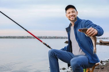 Genç adam nehirde balık tutuyor.