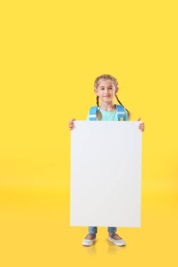 Renk arkaplanı boş afişi olan küçük tatlı bir kız öğrenci.