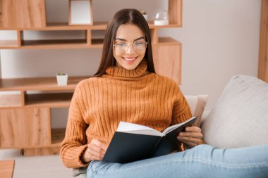 Evde kitap okuyan genç bir kadın.