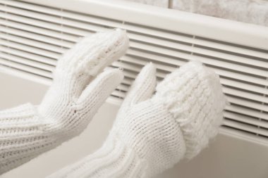 Radyatörde elini ısıtan kadın. Isınma mevsimi kavramı