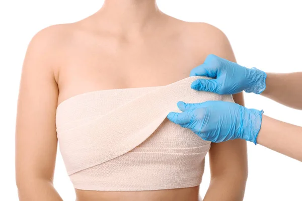 白底美容外科手术后女性胸部贴绷带的医生 — 图库照片