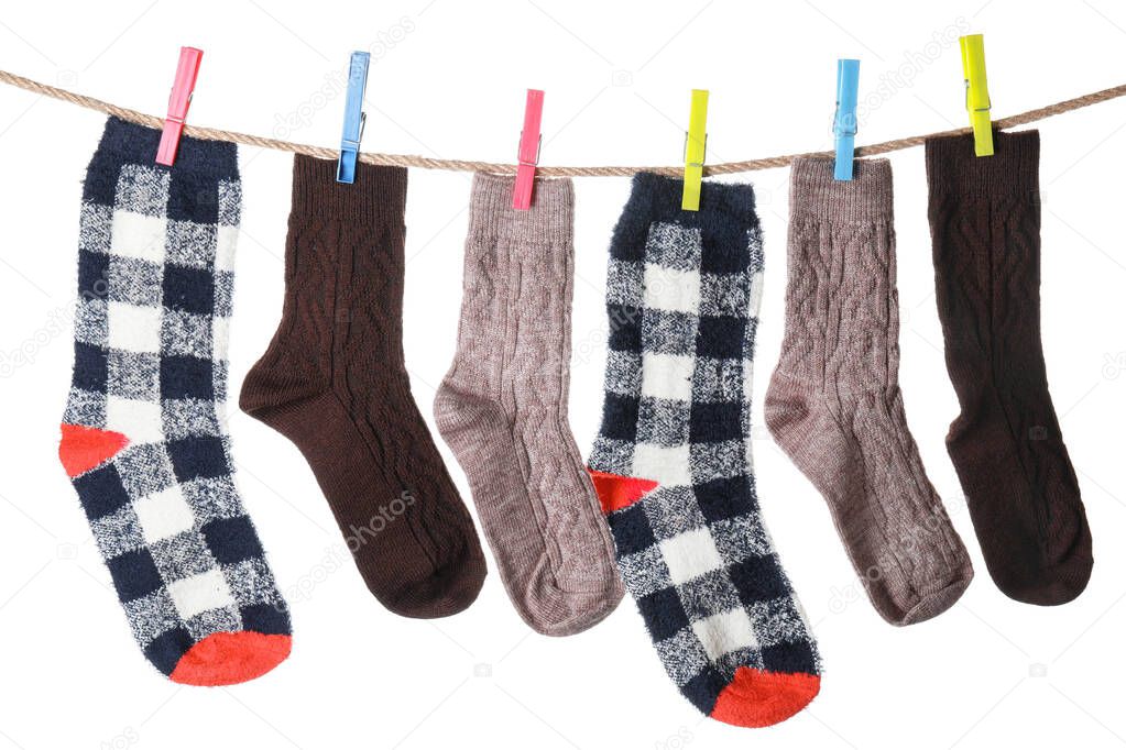 Warm socks hanging on clothes line against white background
