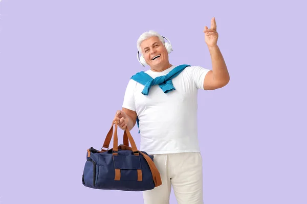 幸せなシニア男でスポーツバッグとヘッドフォンでカラー背景 — ストック写真