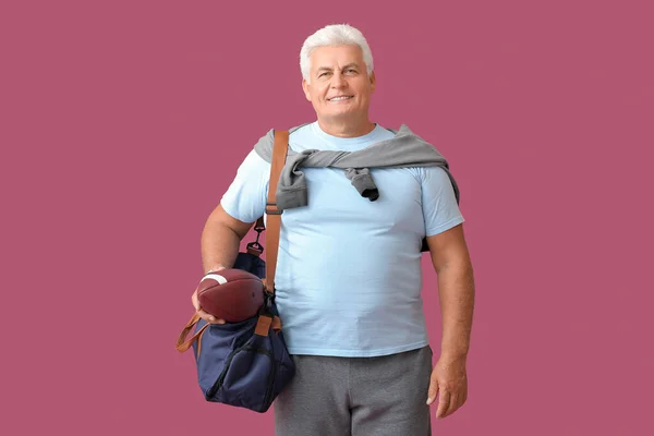 Sportlicher Senior Mit Tasche Und Rugby Ball Auf Farbigem Hintergrund — Stockfoto