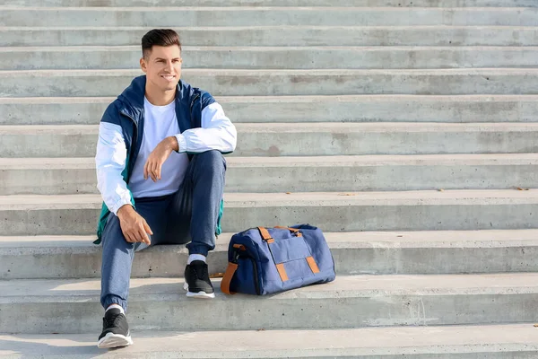 Sporty young man with bag outdoors