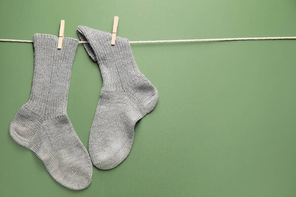 Rope with warm socks on color background